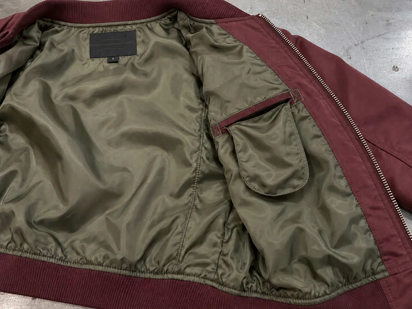 Close-up of polyester taffeta bomber jacket lining with internal pocket, label and zipper facing
