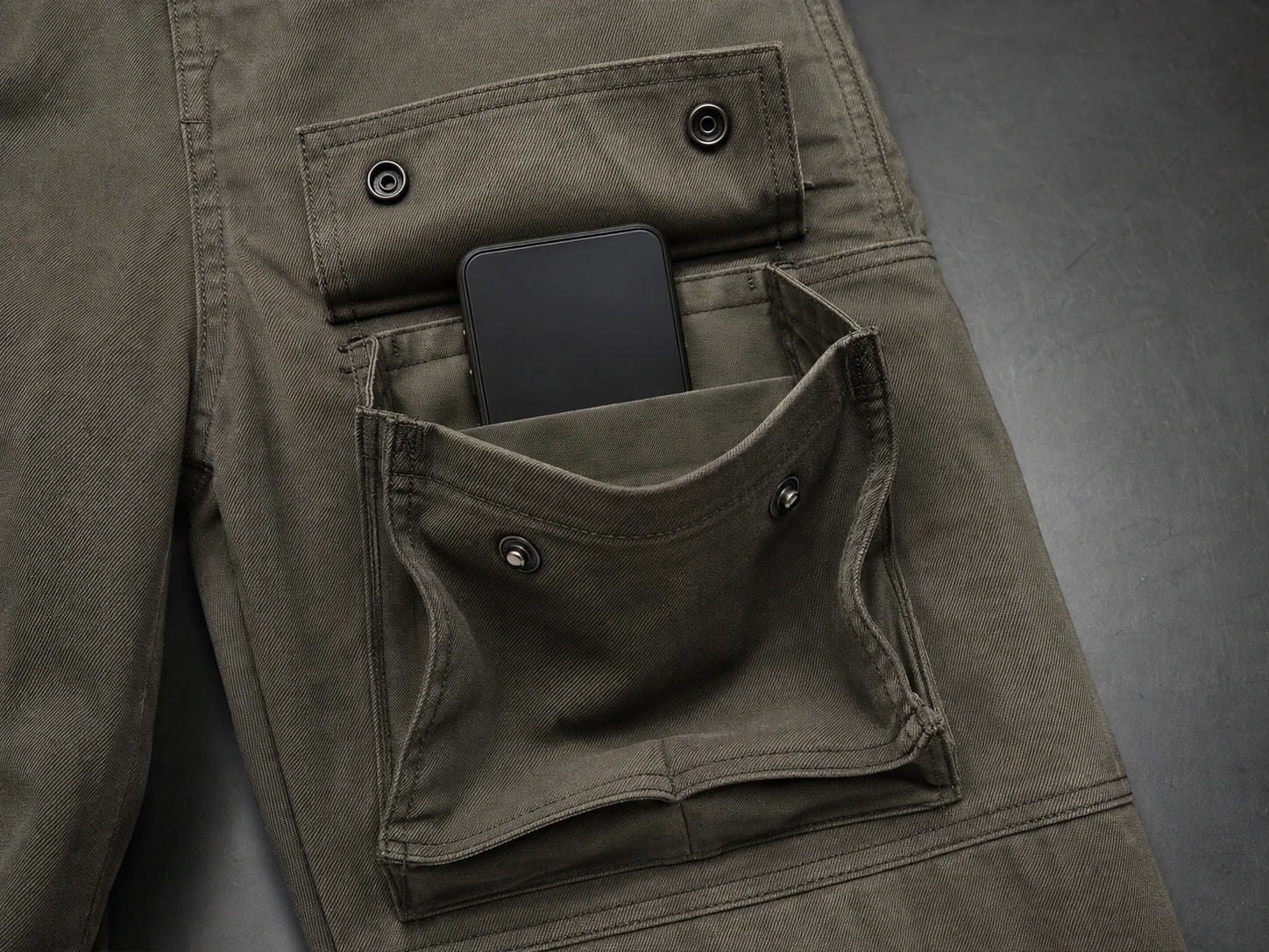 Open three-dimensional cargo pocket holding a smartphone with visible side gussets and internal divider