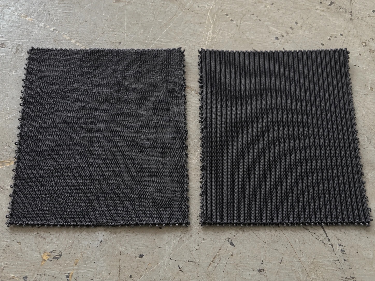 Dark main knit swatch beside a ribbed trim swatch on a factory worktable