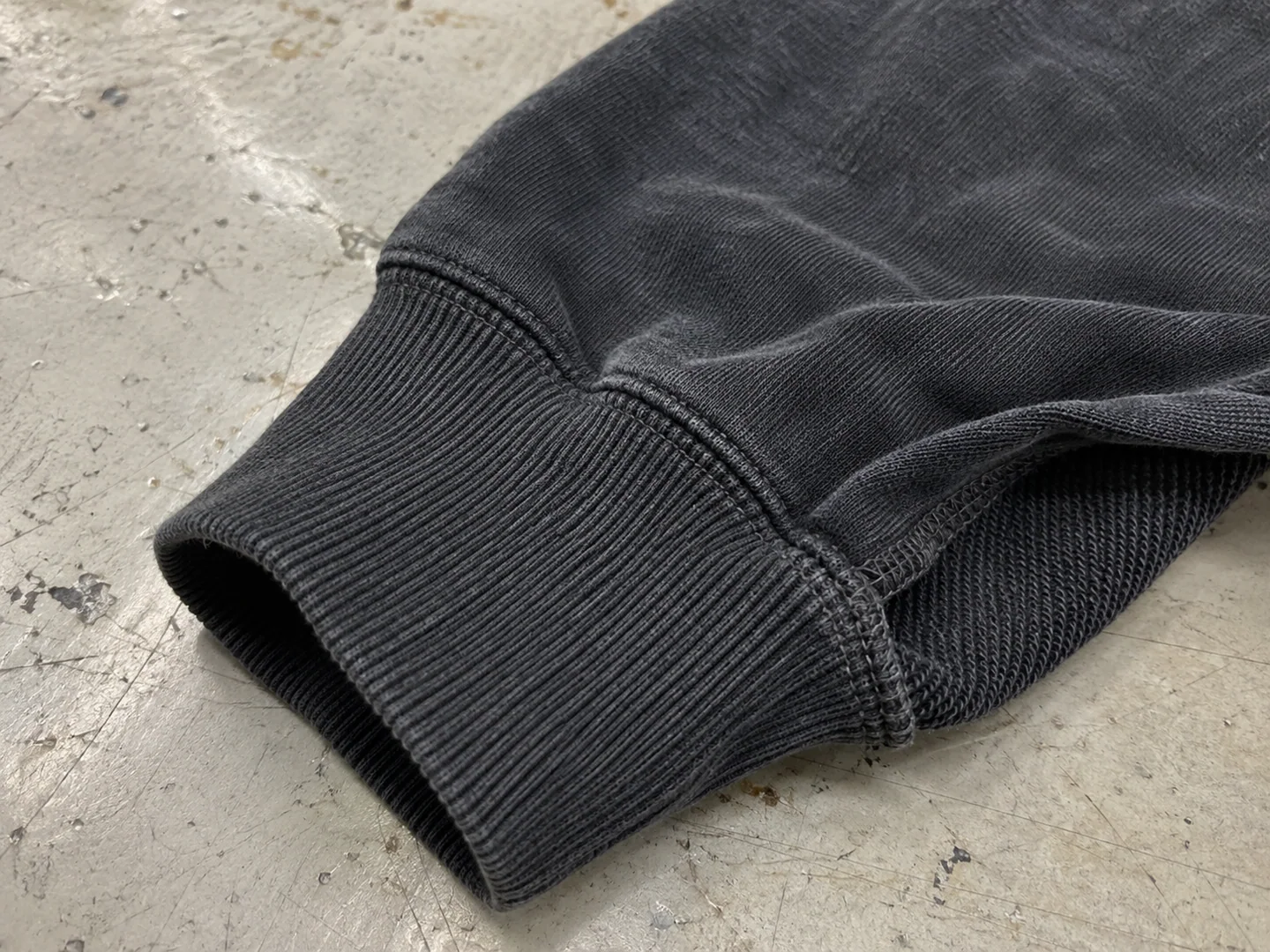 Close-up of a washed black hoodie cuff with fine ribbing and attached sleeve seam