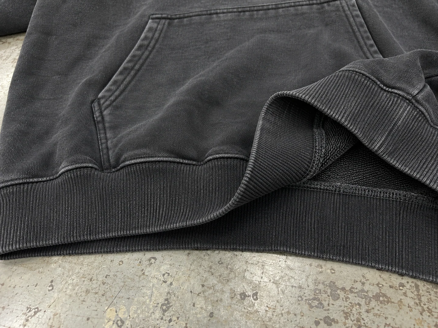 Washed black hoodie hem rib shown from the outside and inside with seam construction visible