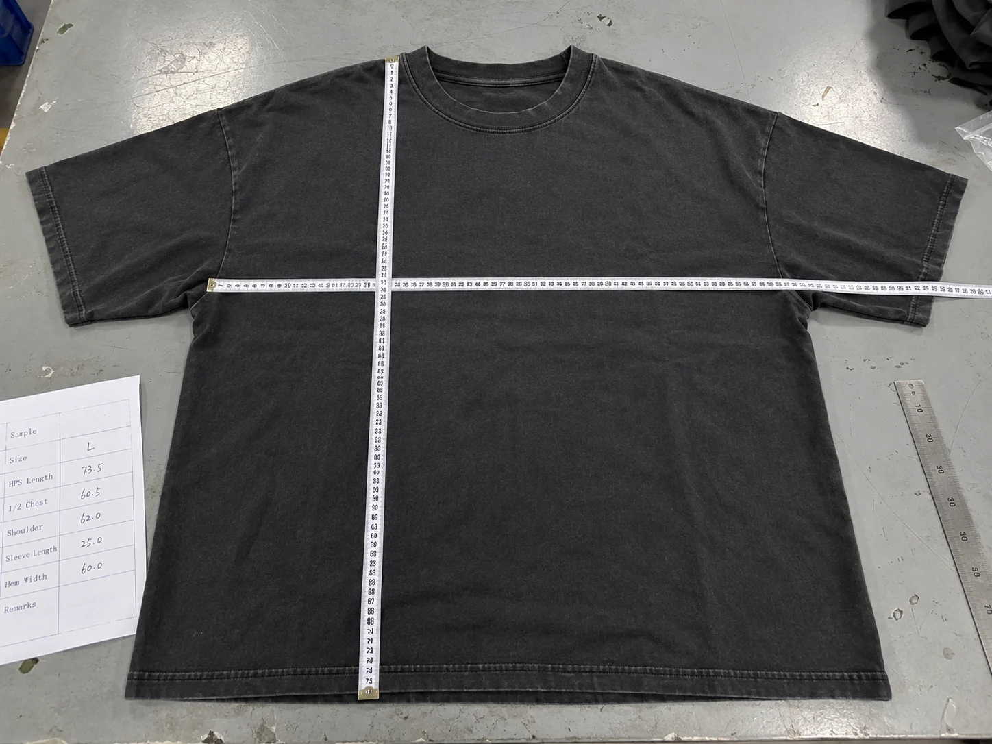 Washed oversized T-shirt laid flat with tapes checking HPS body length, chest and shoulder width
