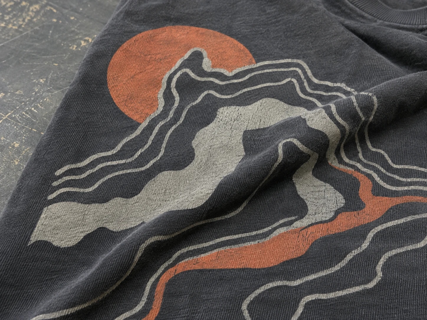 Close view of a distressed multicolor screen print on black cotton fabric