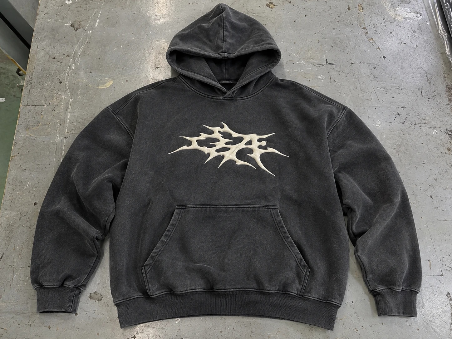 Complete washed dark pullover hoodie with a cream chest graphic and kangaroo pocket