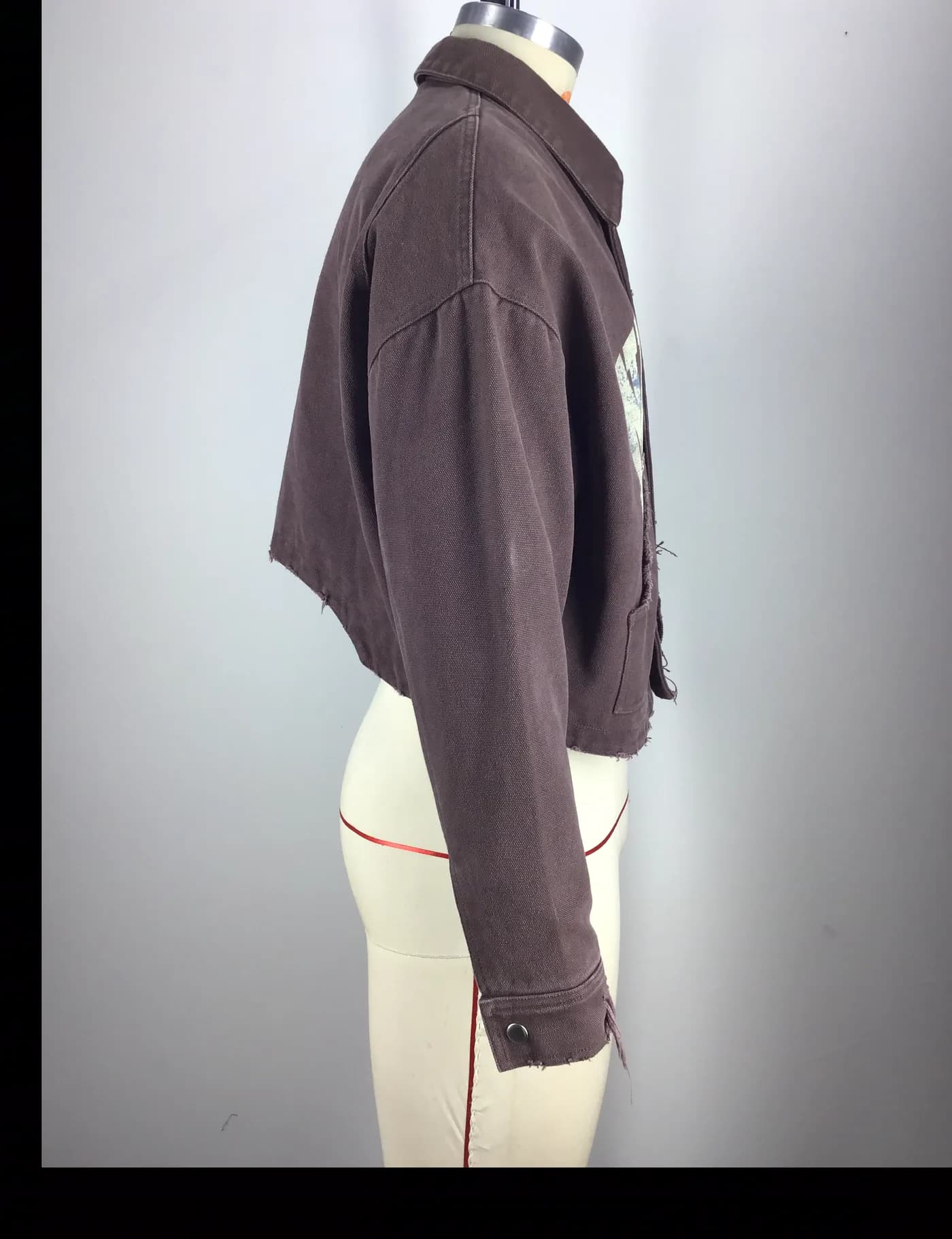 Actual brown cropped graphic workwear jacket sample shown from the side on a mannequin