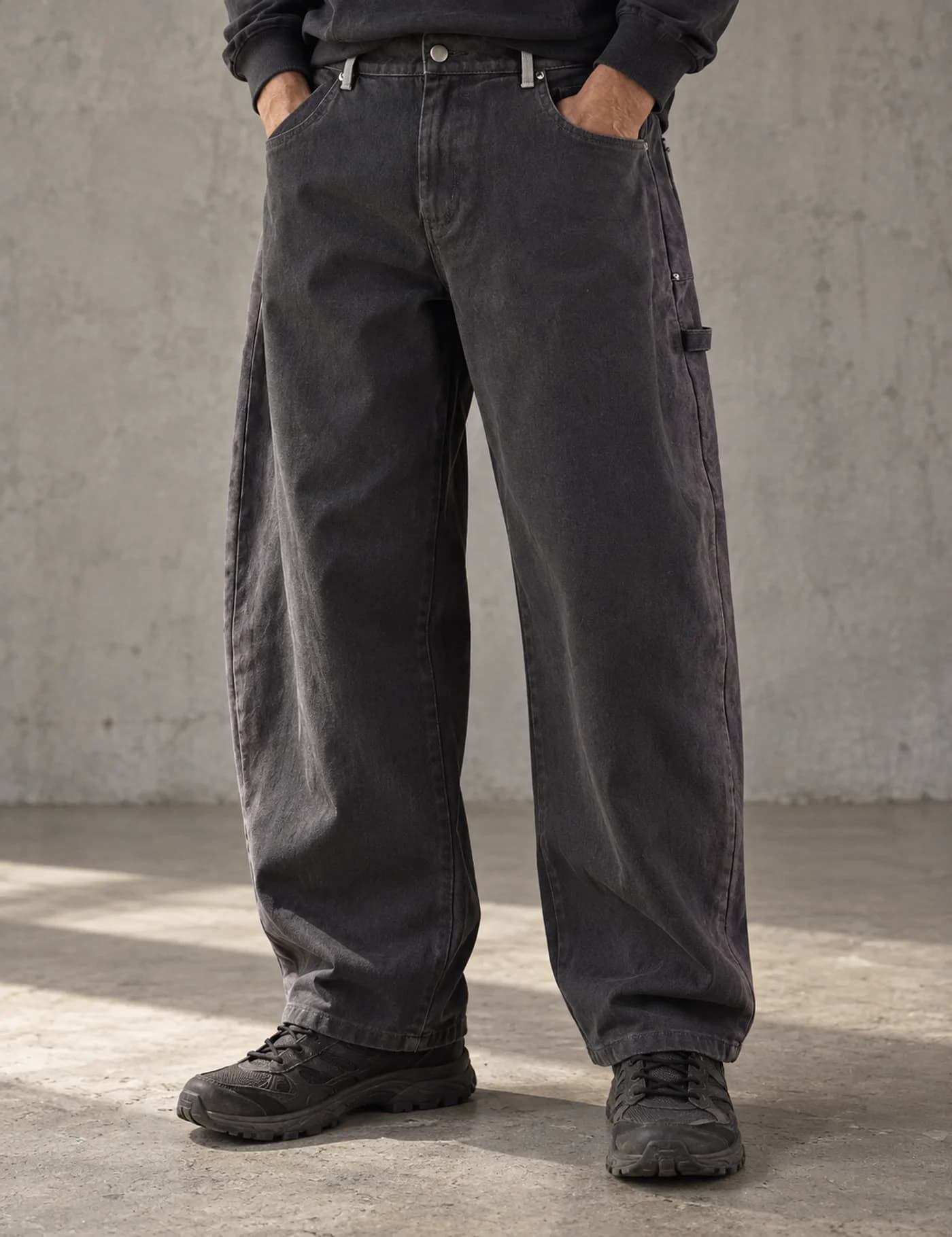 Male model wearing charcoal washed barrel-leg workwear pants with utility pocket details