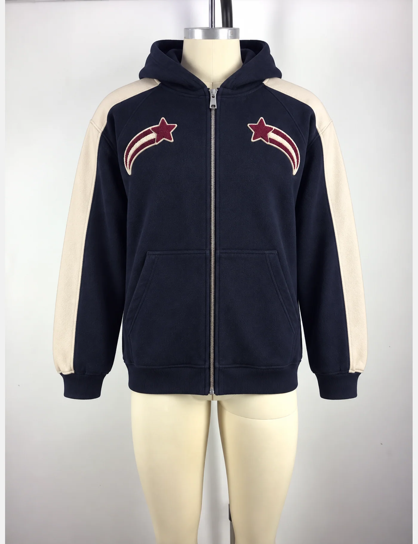 Navy full-zip hoodie on a mannequin with cream sleeve panels, shooting-star chest patches and split front pockets