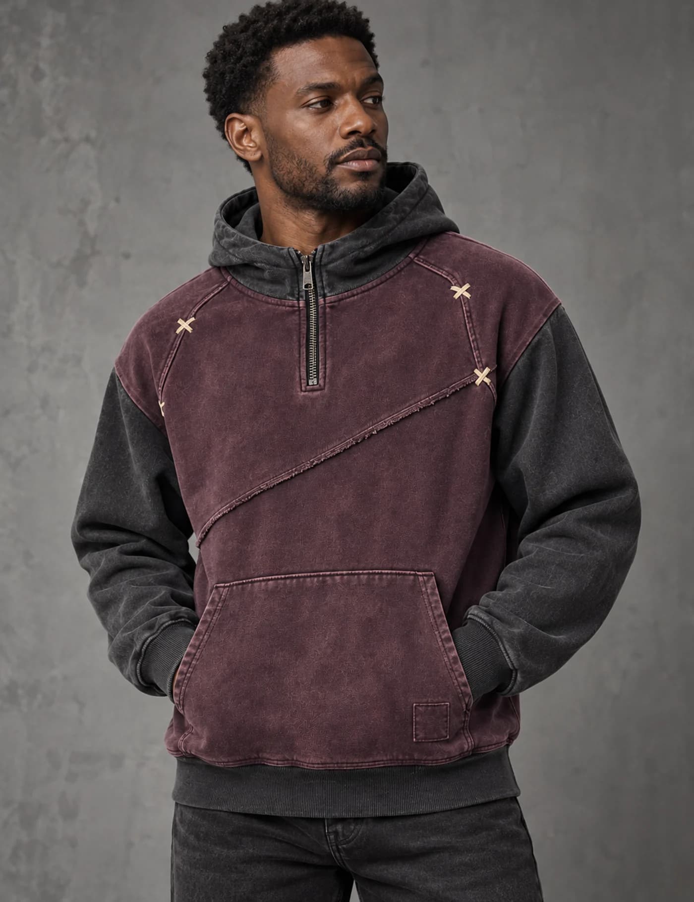 Black male model wearing a washed burgundy and charcoal color-block quarter-zip hoodie