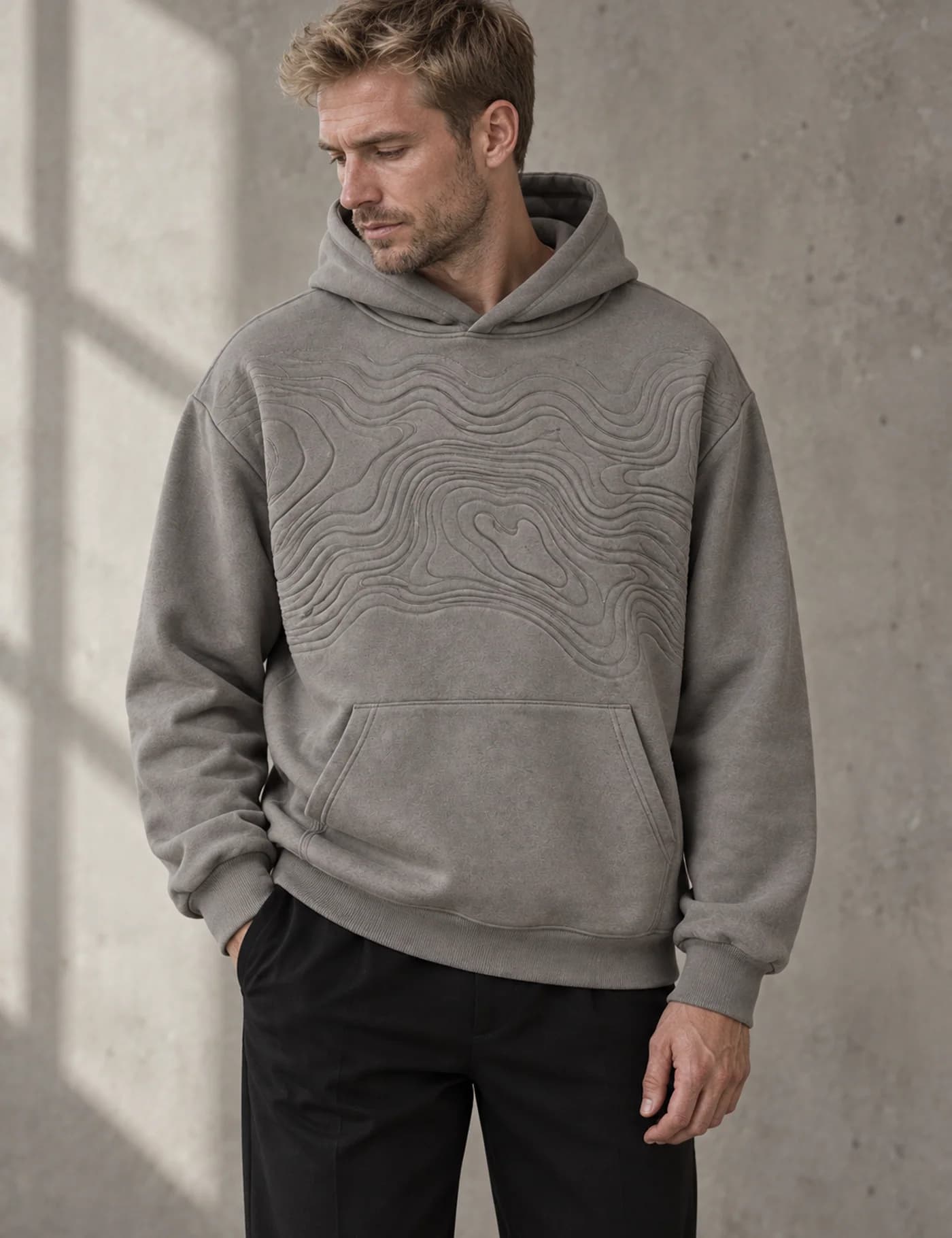 Blond European male model wearing a gray pullover hoodie with tonal topographic contour quilting