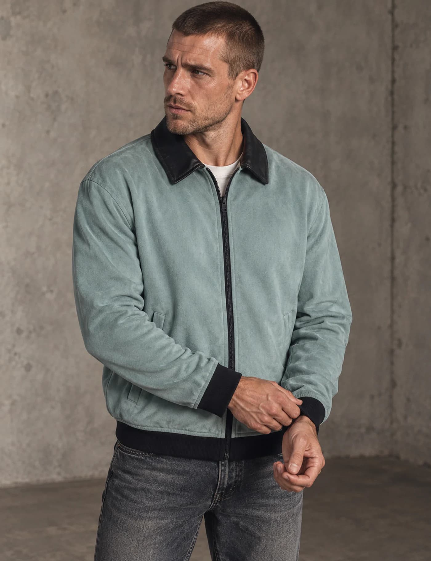 Male model wearing a pale blue-green bomber jacket with a black pointed collar, zipper and rib trims
