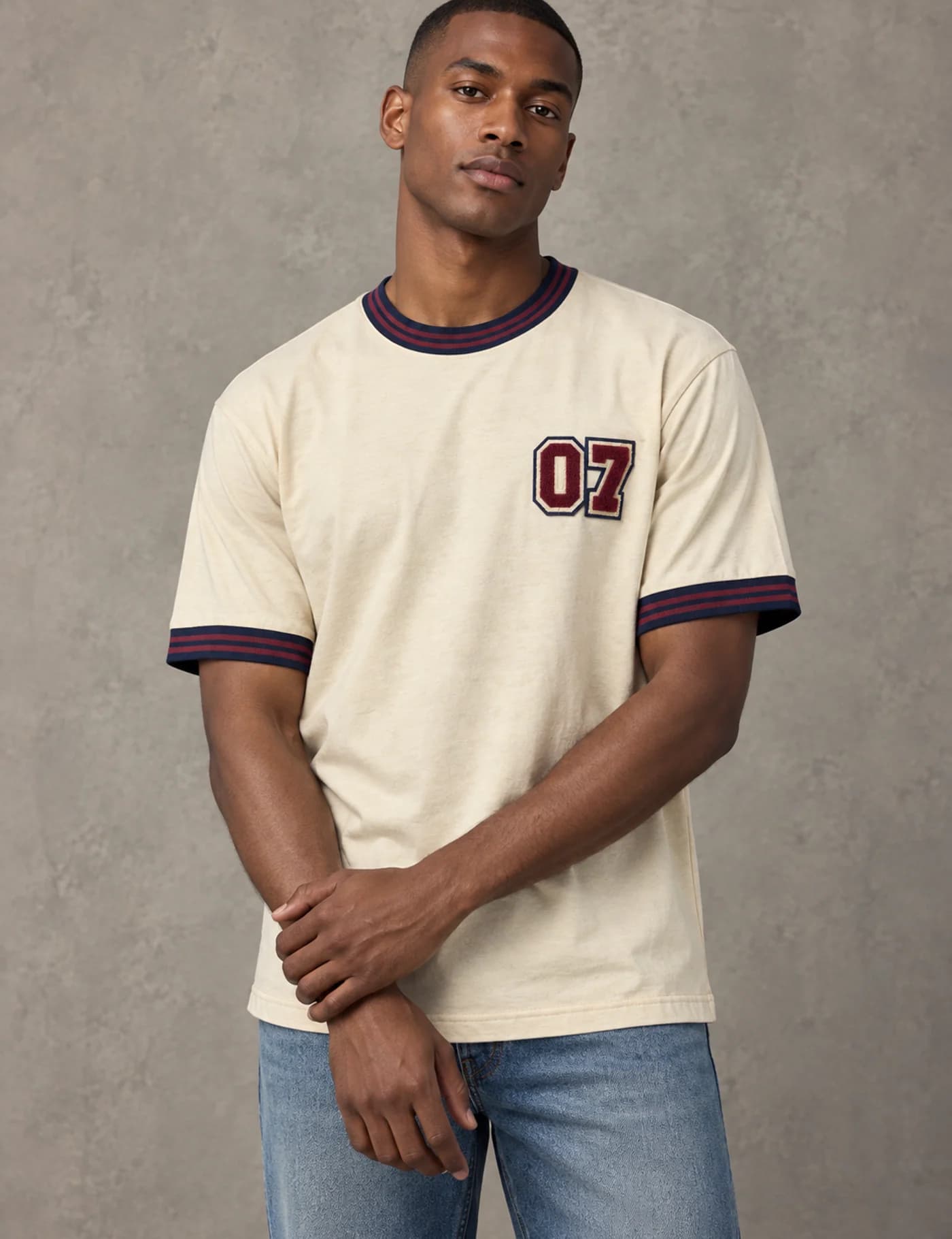 Male model wearing a cream ringer T-shirt with burgundy trims and raised 07 chenille embroidery