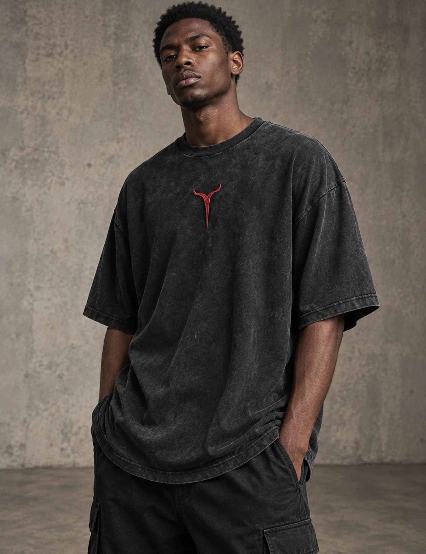Male model wearing a washed black oversized T-shirt with small red chest embroidery
