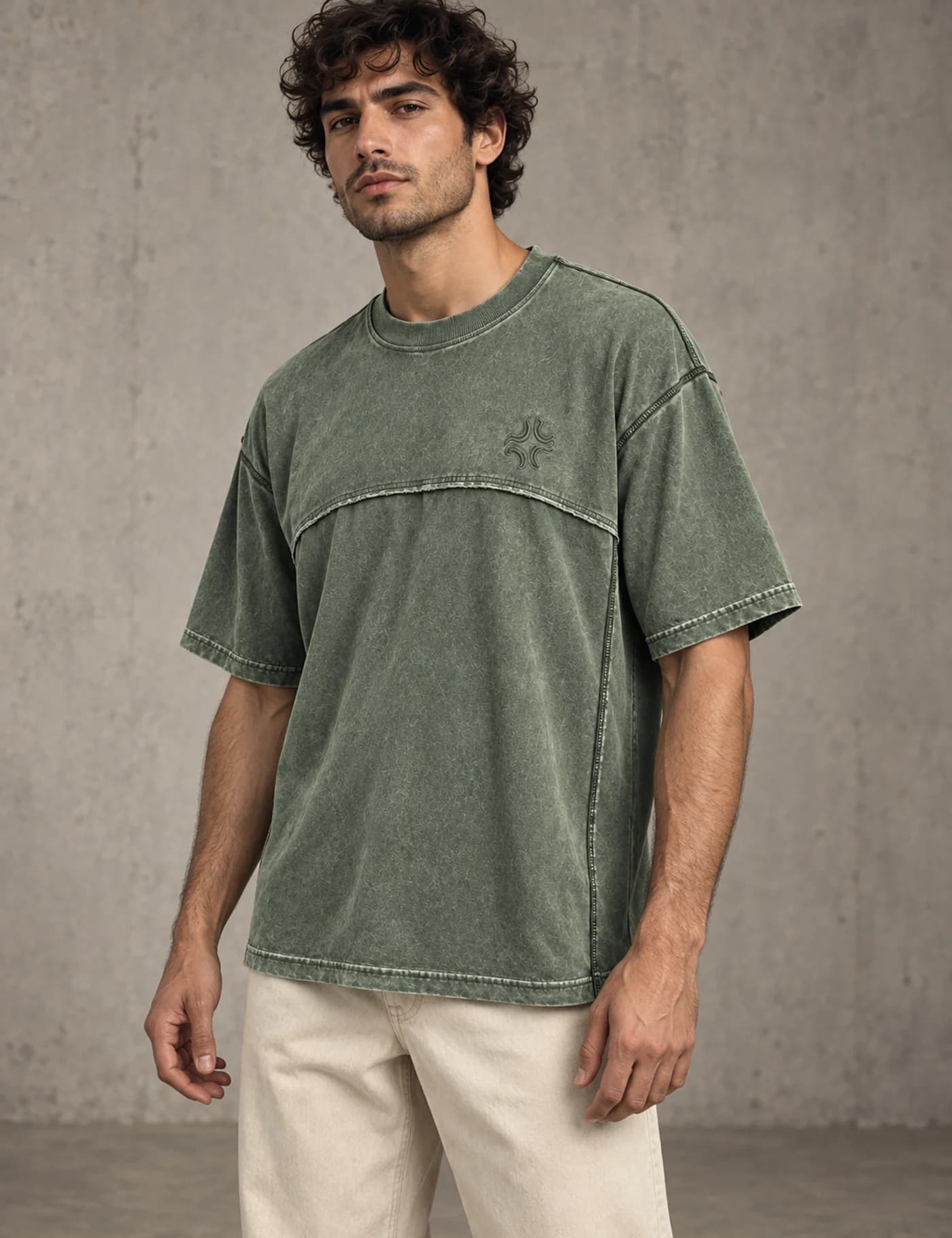 Male model wearing a muted green washed oversized T-shirt with visible yoke and panel seams