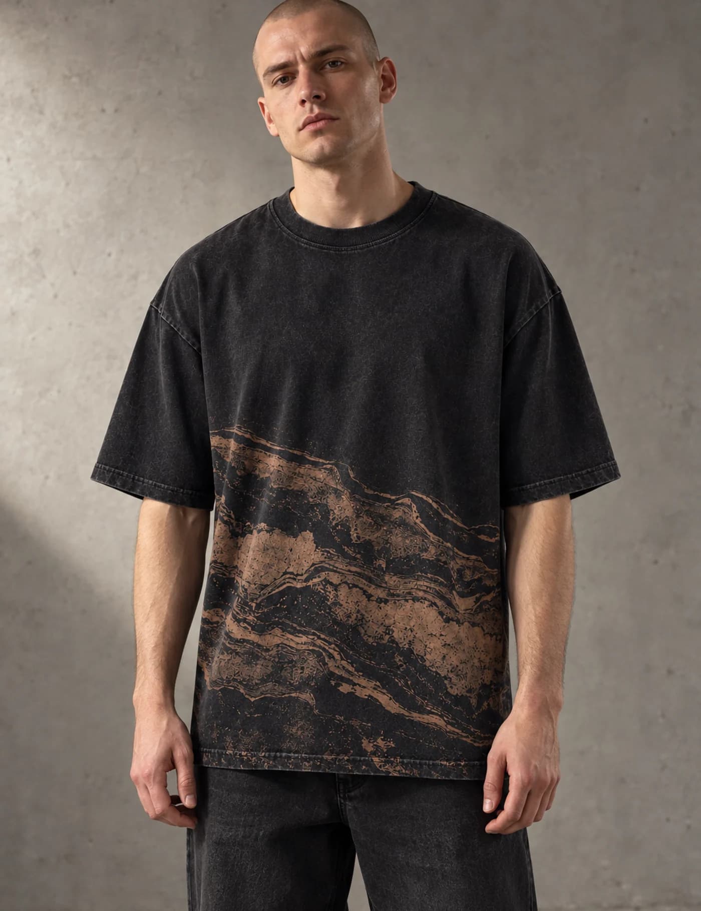Male model wearing a black washed oversized T-shirt with a large brown mapped lower-body graphic