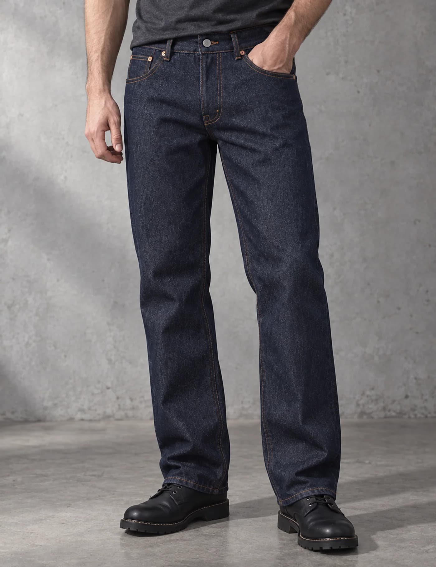 Male lower-body model wearing clean dark indigo straight-leg jeans with tobacco stitching
