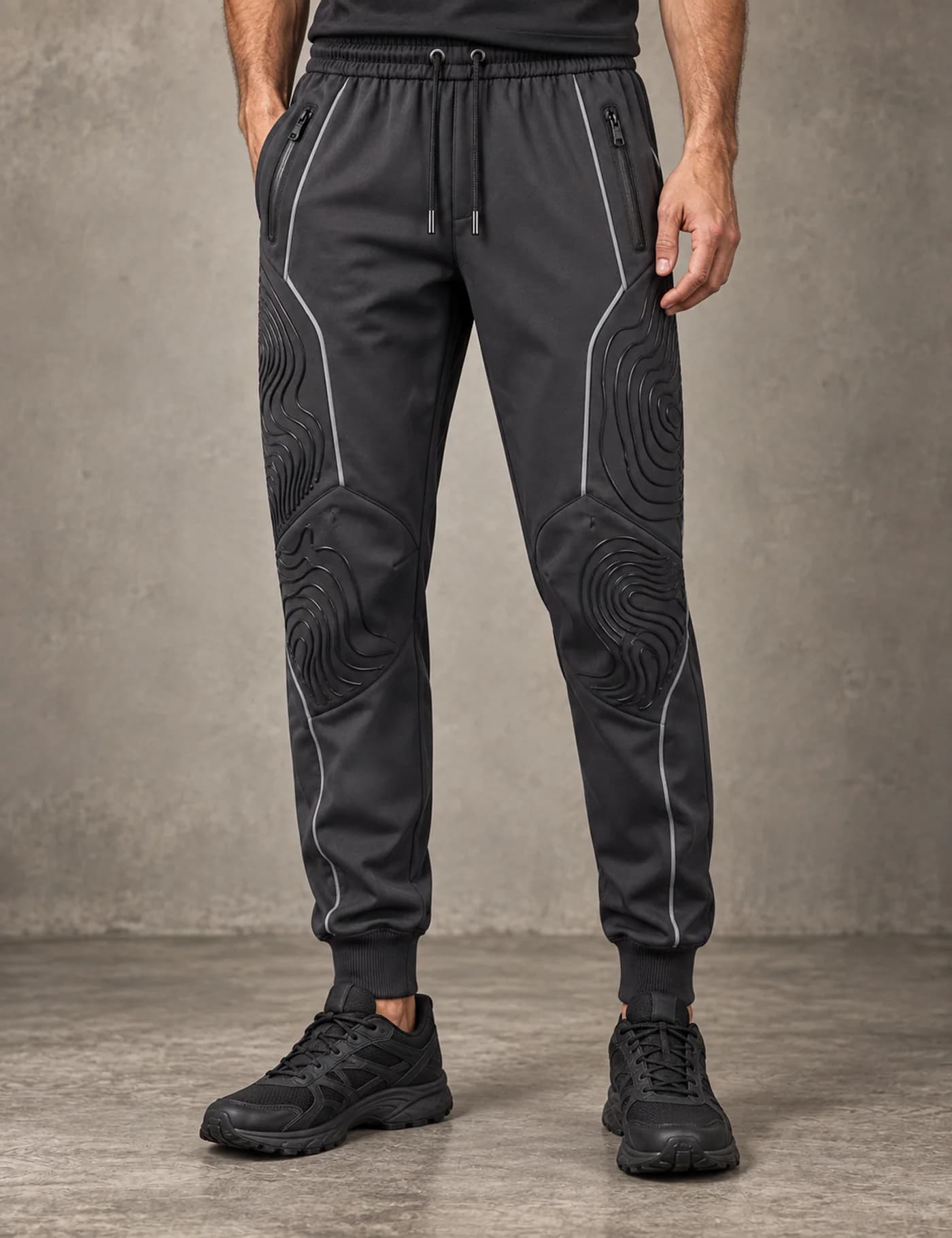 Male lower-body model wearing charcoal technical joggers with raised contour knee panels