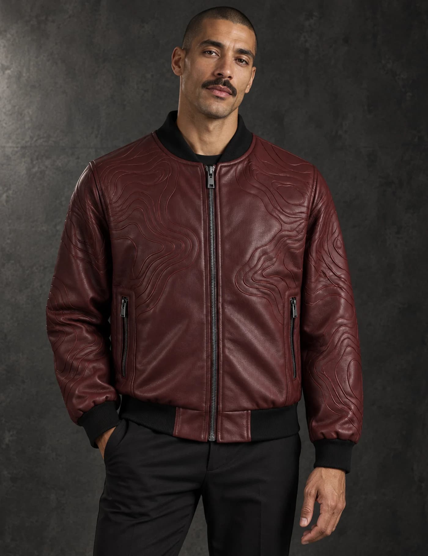 Mixed-race male model wearing a burgundy faux-leather bomber jacket with embossed wave texture