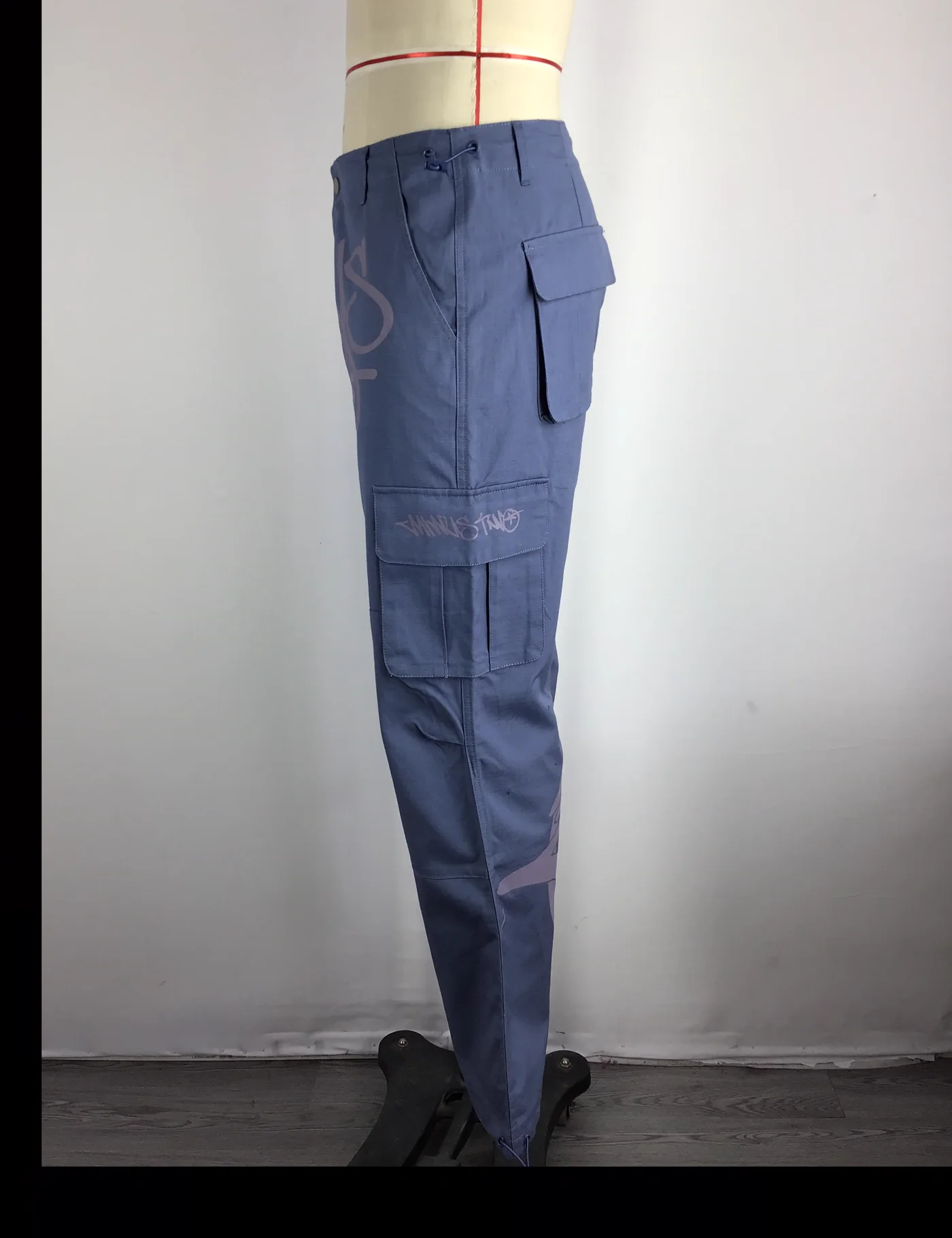 Actual graphic wide-leg cargo pants sample shown from the side on a mannequin