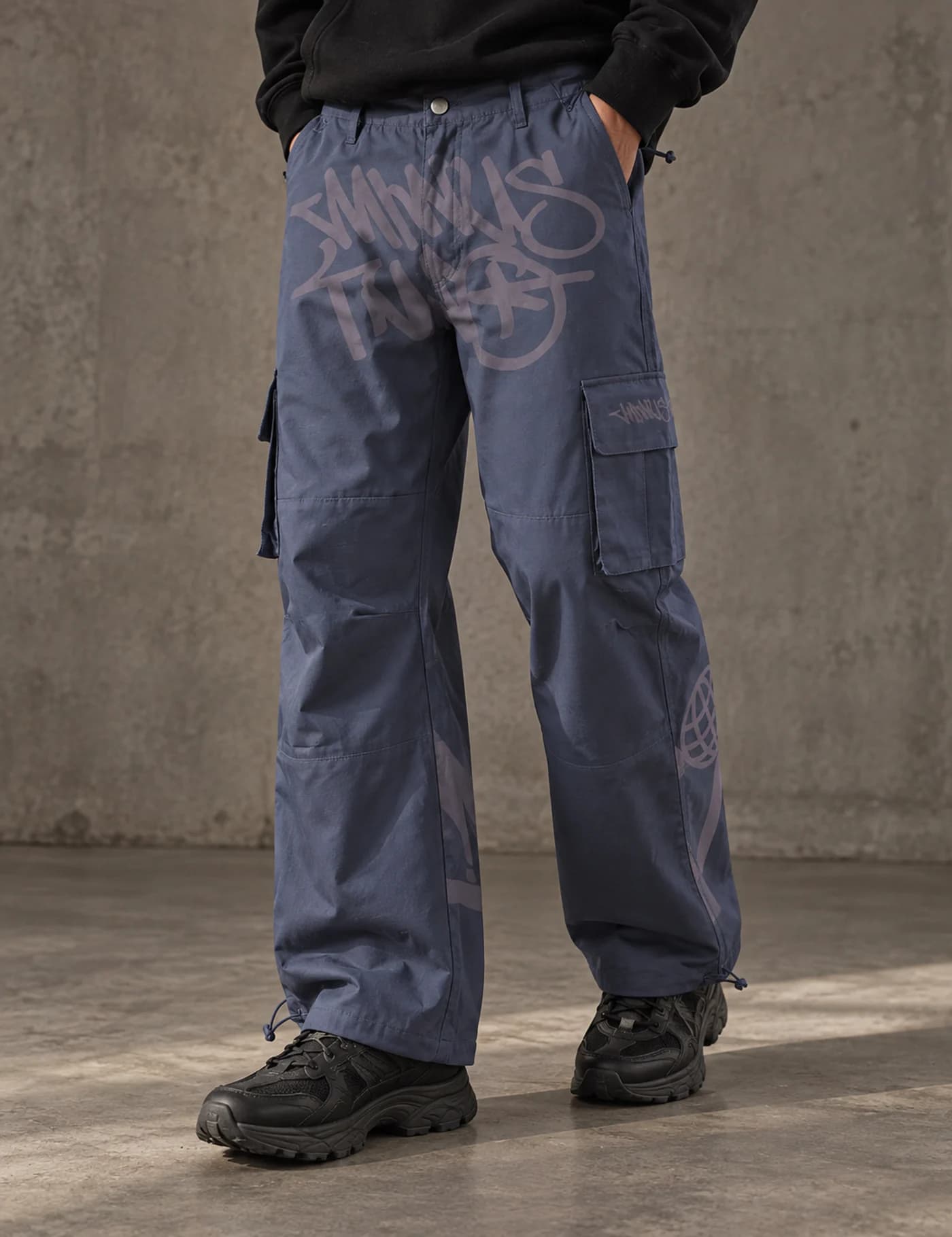 Male model wearing slate-blue wide-leg cargo pants with pale graphic placement