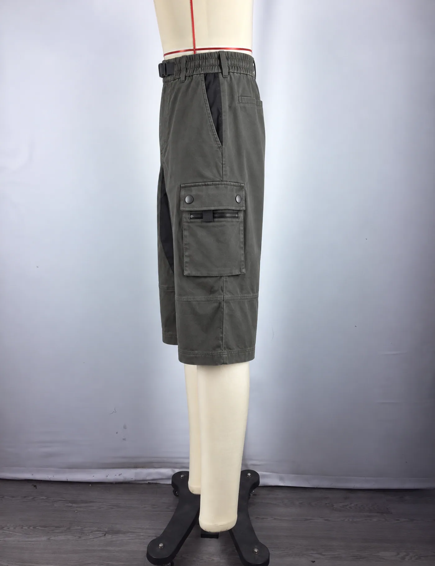 Actual multi-pocket belted cargo shorts sample shown from the side on a mannequin