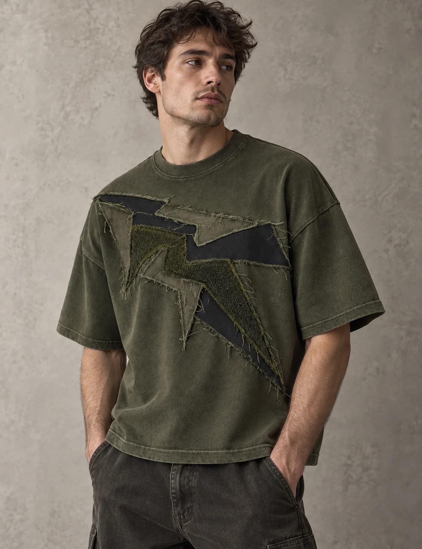Male model wearing a washed olive oversized T-shirt with layered raw-edge appliqué