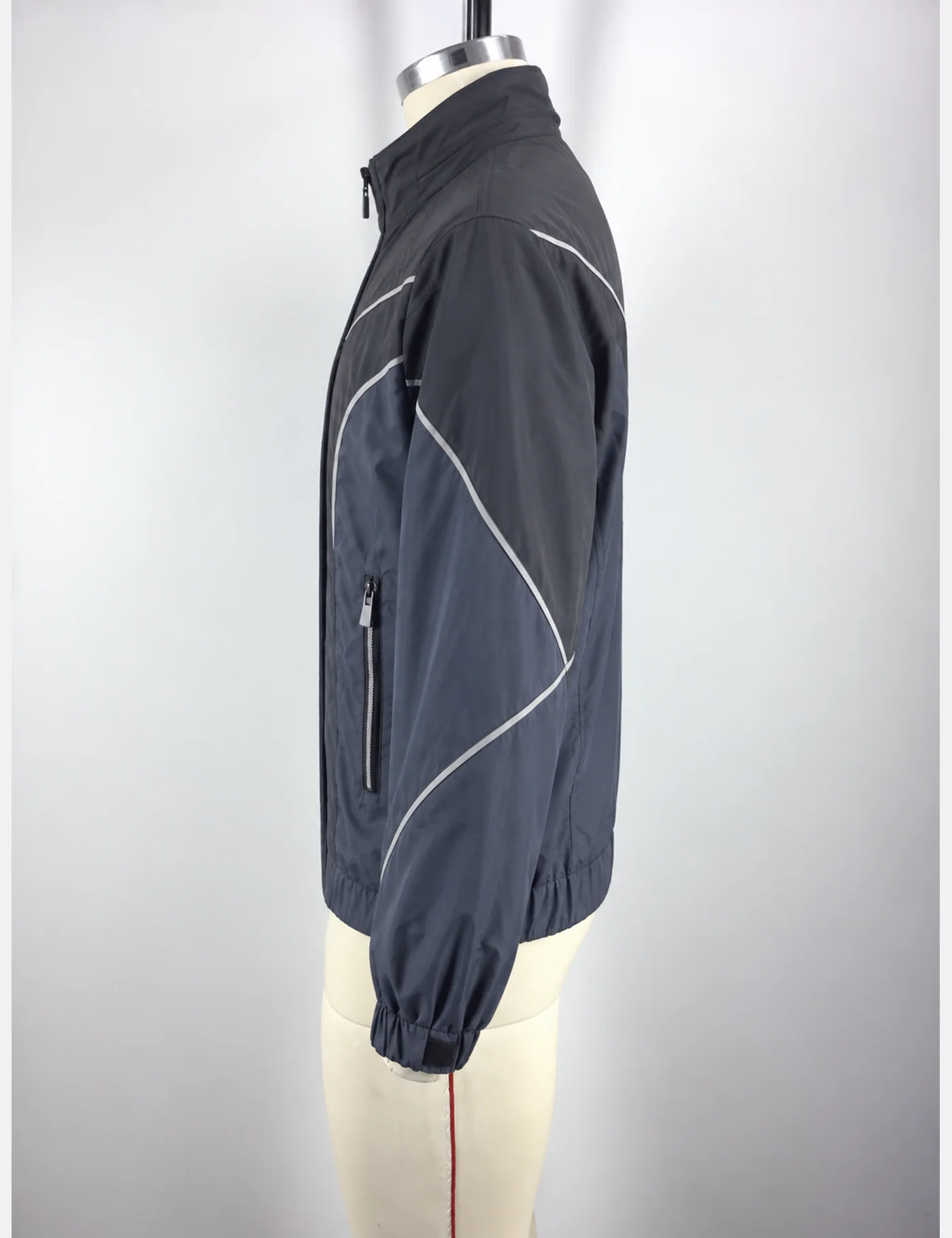 Actual reflective curved-panel windbreaker jacket sample shown from the side on a mannequin