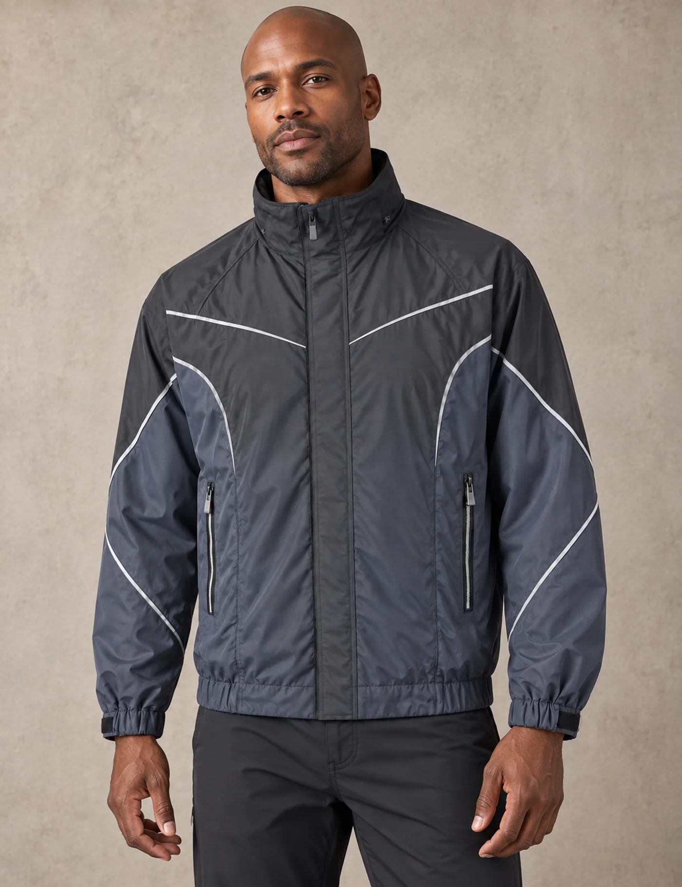 Male model wearing a charcoal and slate windbreaker with curved reflective piping