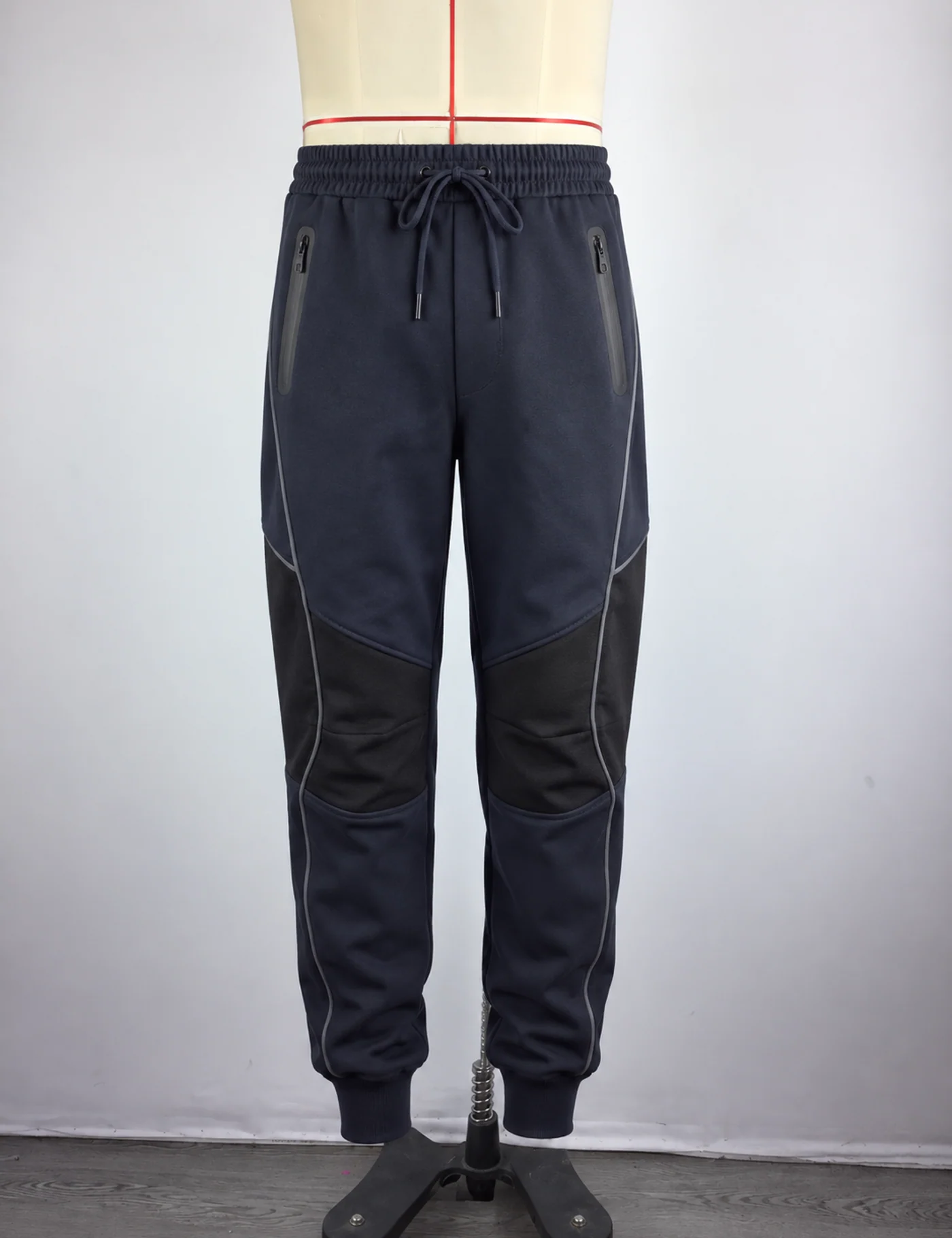 Actual reflective-panel technical joggers sample shown from the front on a mannequin