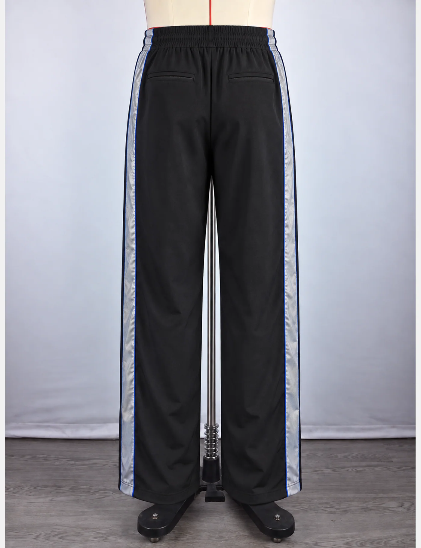 Actual reflective side-stripe wide-leg track pants sample shown from the back on a mannequin
