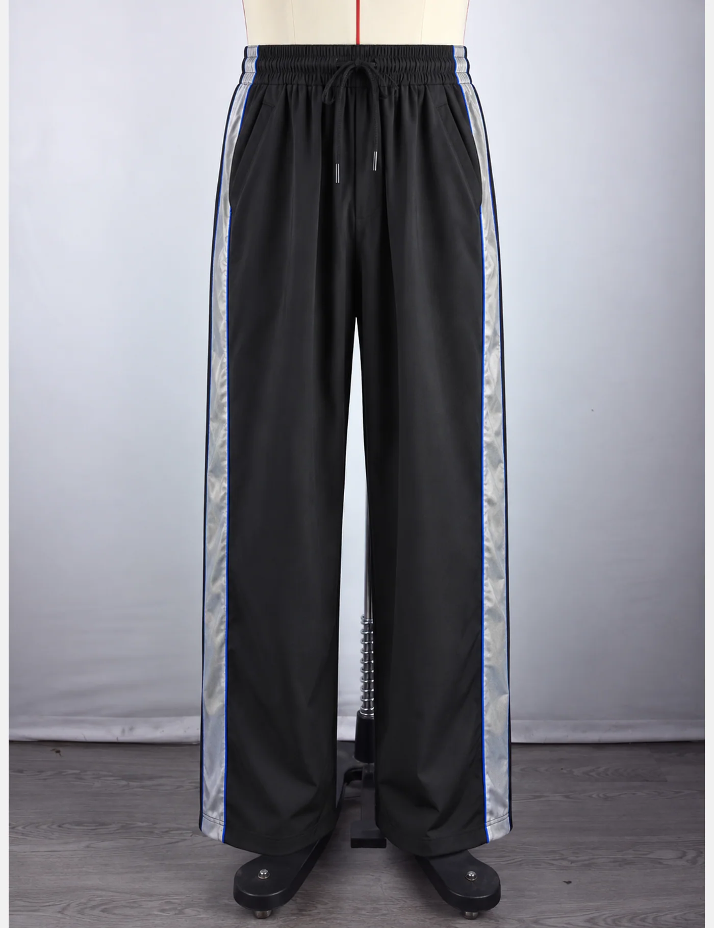 Actual reflective side-stripe wide-leg track pants sample shown from the front on a mannequin