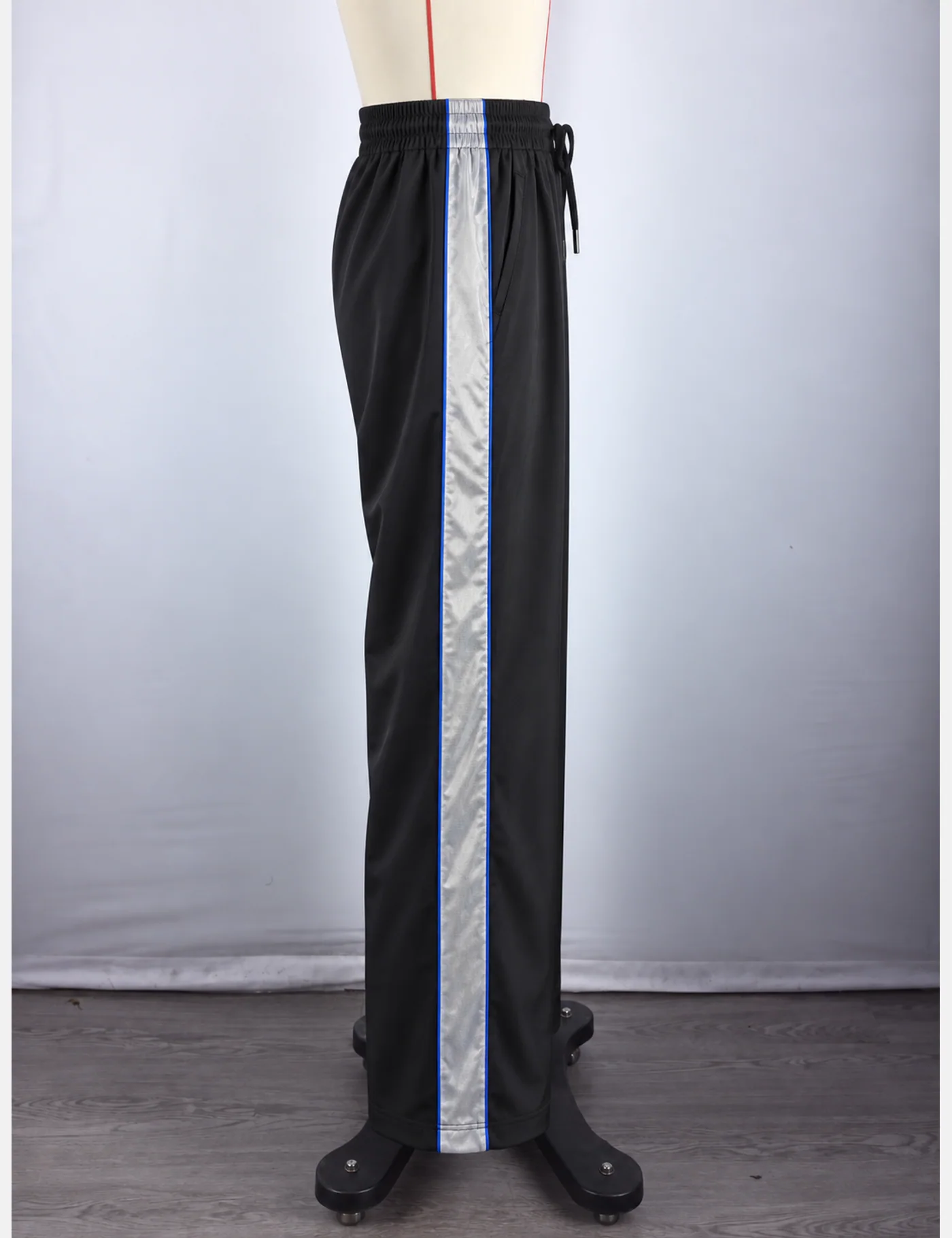 Actual reflective side-stripe wide-leg track pants sample shown from the side on a mannequin