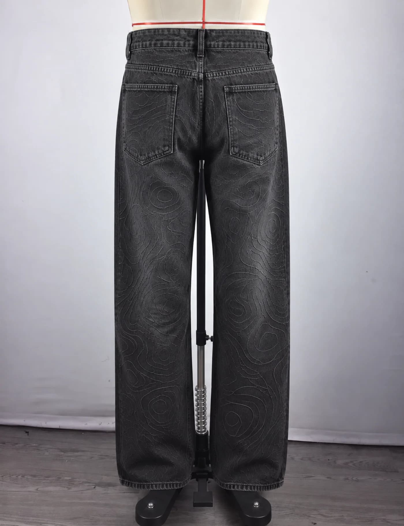 Actual topographic pattern wide-leg jeans sample shown from the back on a mannequin