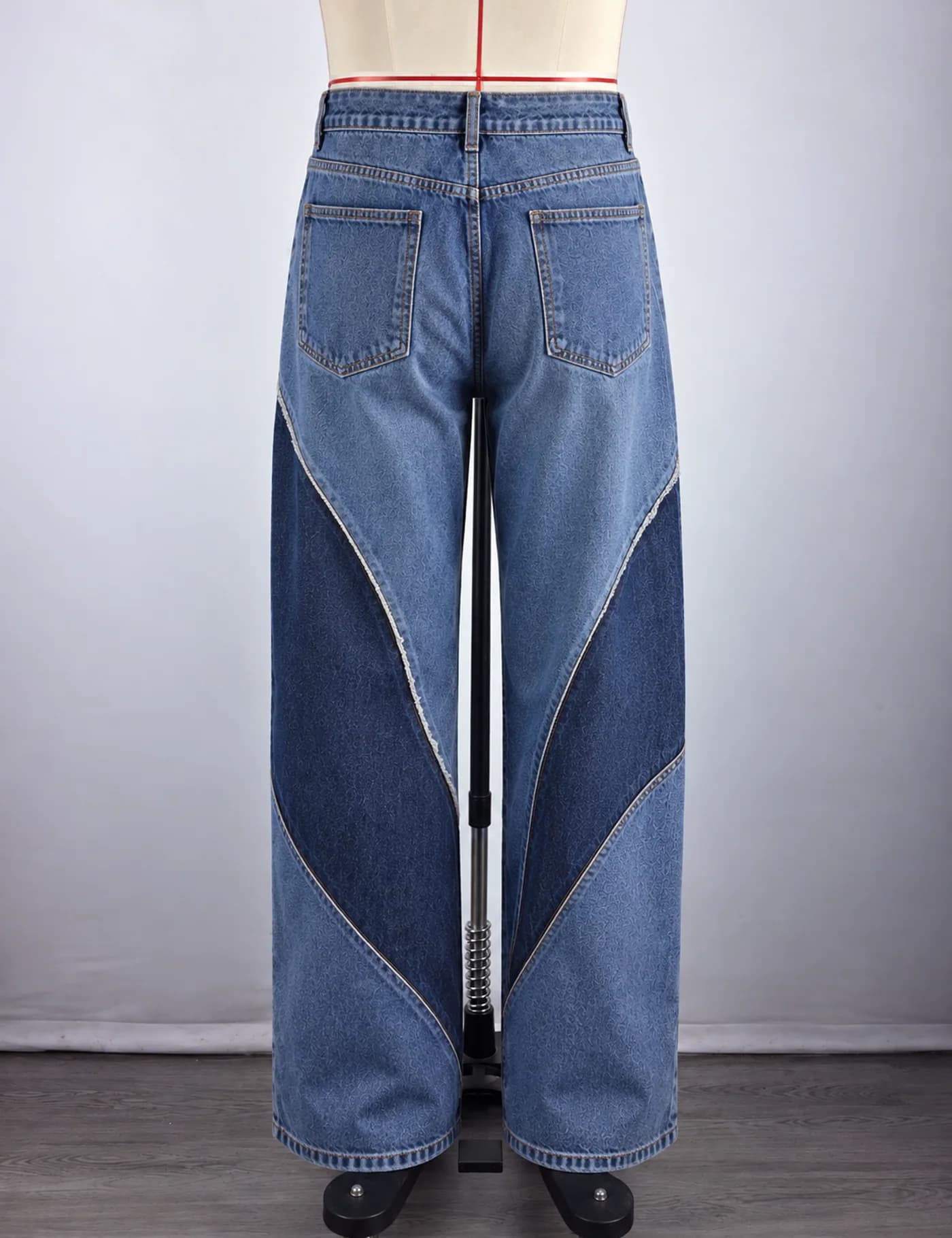 Actual two-tone curved-panel wide-leg jeans sample shown from the back on a mannequin
