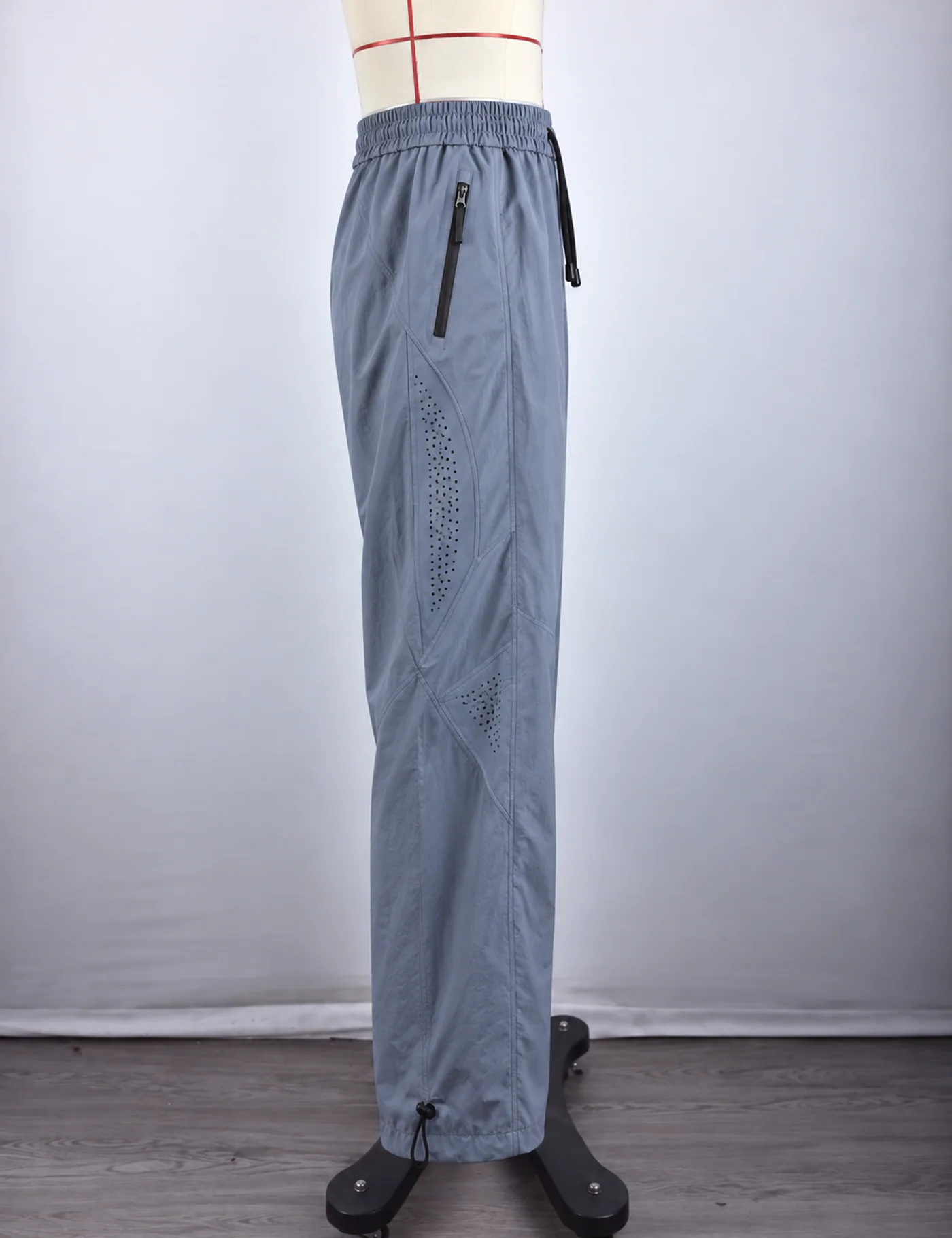 Actual ventilated wide-leg track pants sample shown from the side on a mannequin