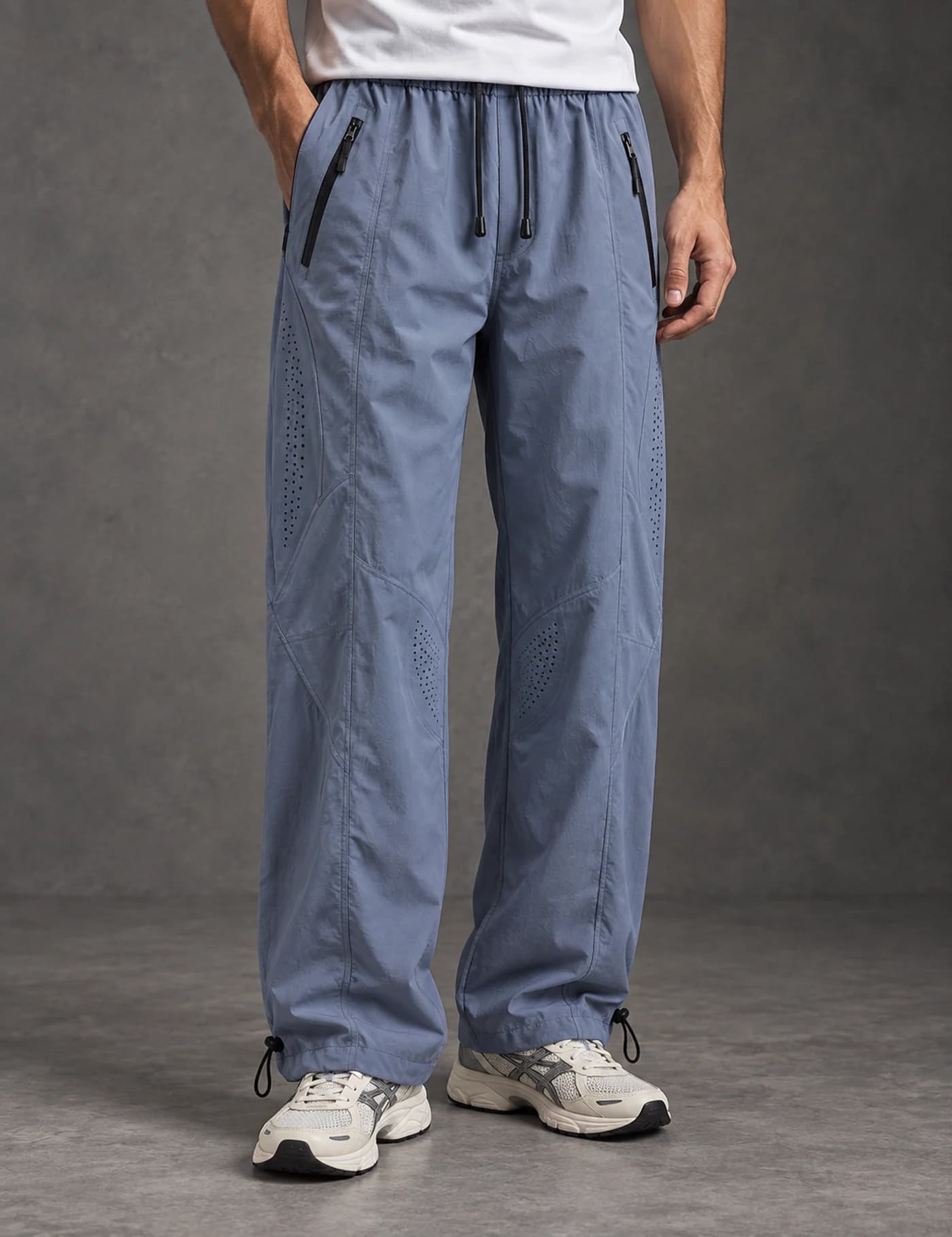 Male model wearing slate blue ventilated wide-leg track pants with zip pockets