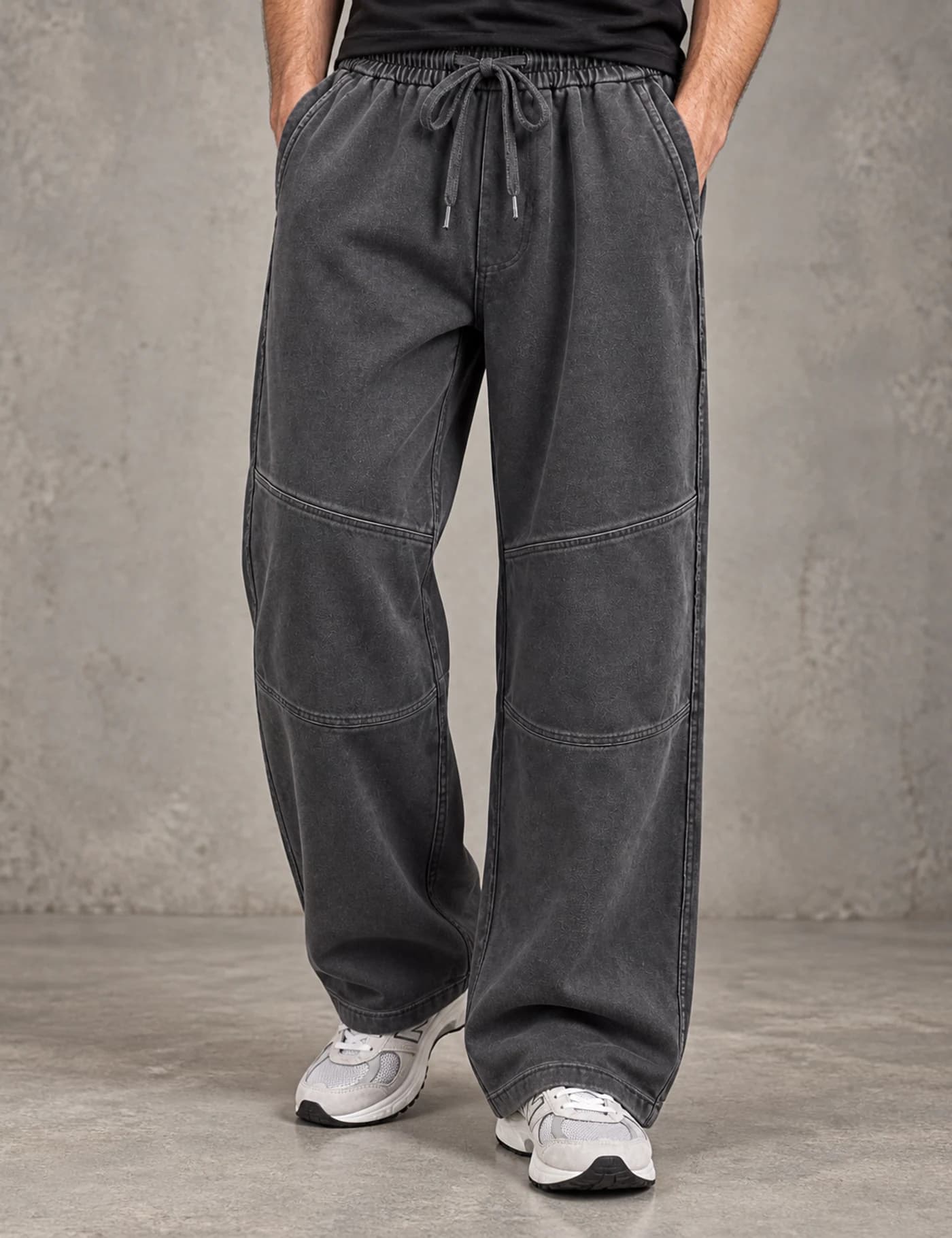 Male lower-body model wearing washed charcoal wide-leg sweatpants with articulated knee seams