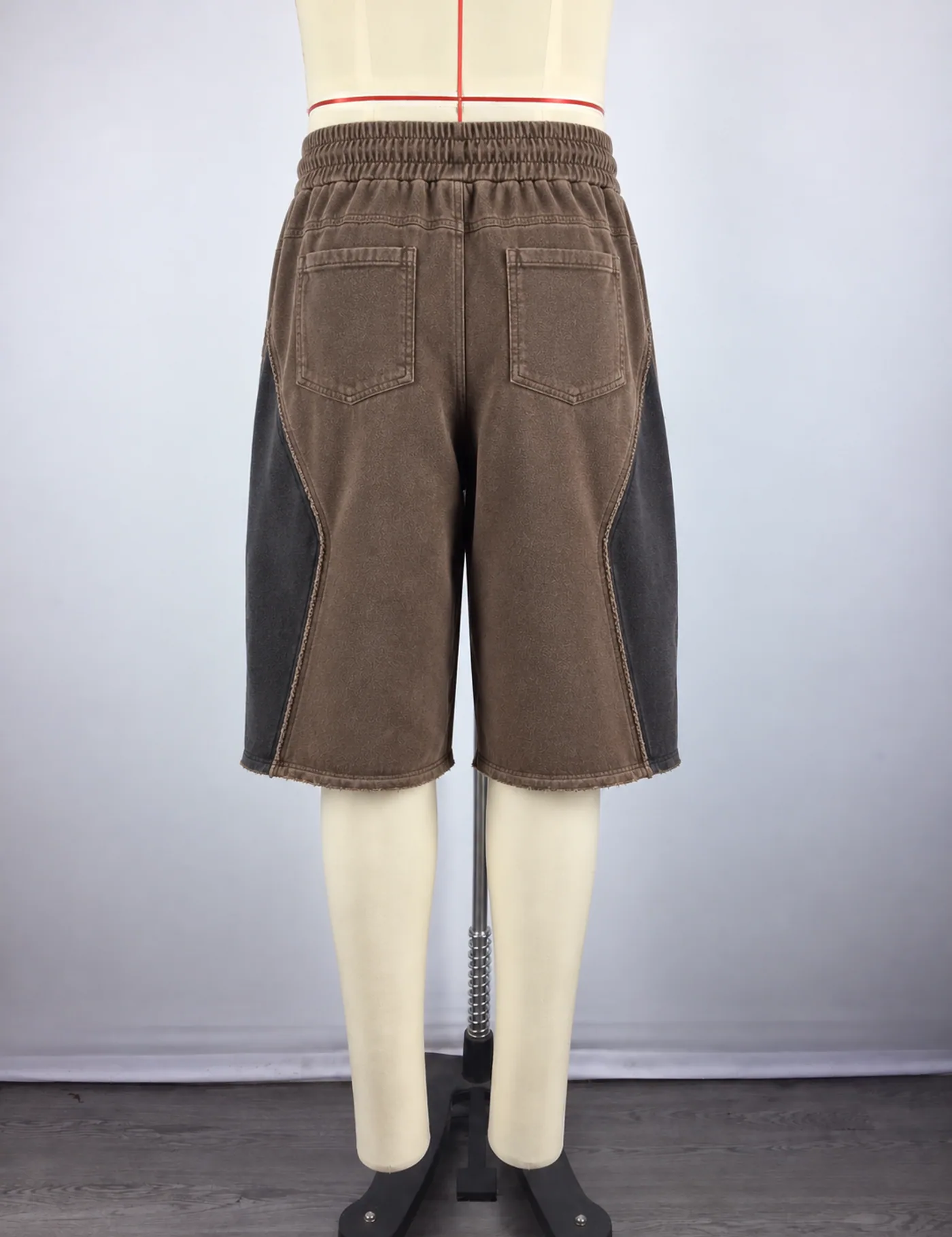 Actual washed color-block long shorts sample shown from the back on a mannequin