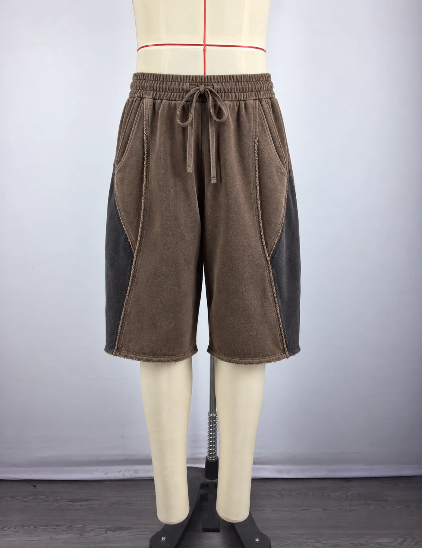 Actual washed color-block long shorts sample shown from the front on a mannequin
