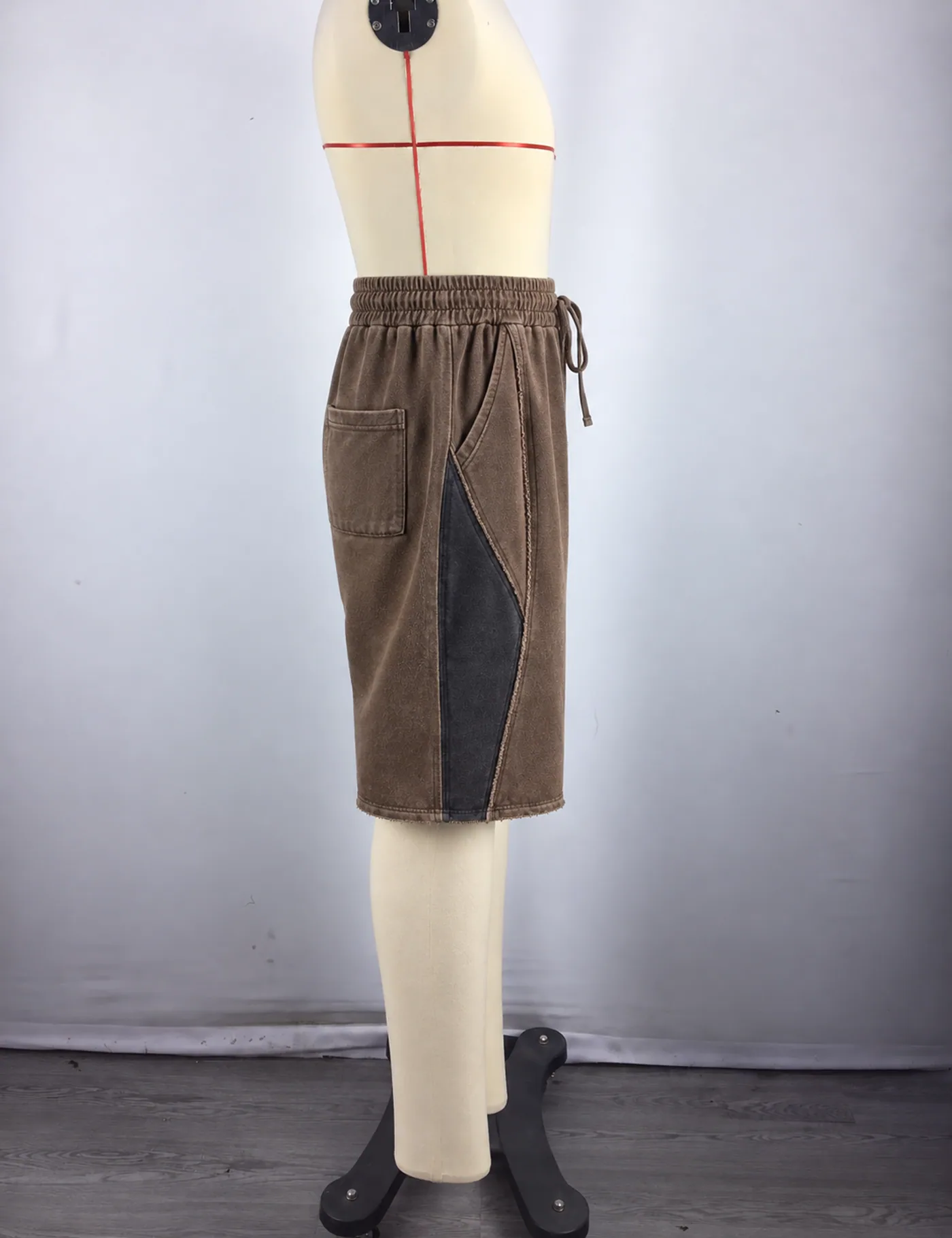Actual washed color-block long shorts sample shown from the side on a mannequin