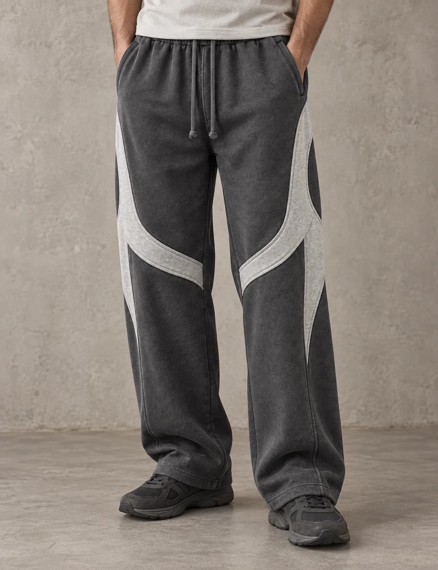 Male lower-body model wearing washed charcoal wide-leg sweatpants with light grey curved panels