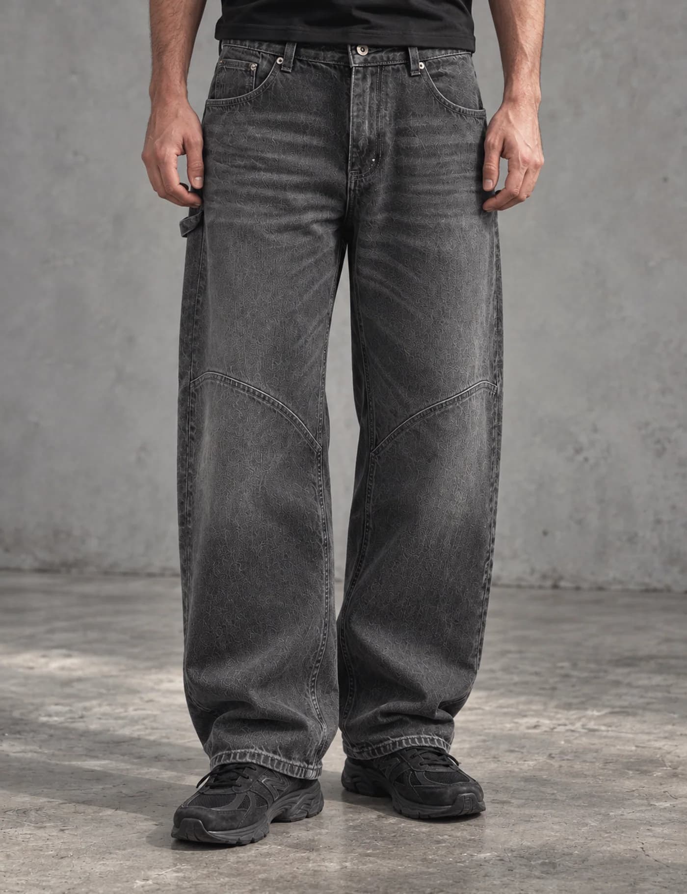 Male lower-body model wearing washed charcoal wide-leg carpenter jeans with curved knee panels