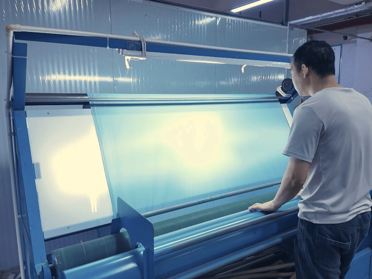 KAOUYOU quality inspector examining incoming fabric on an inspection machine