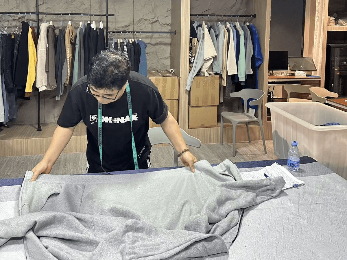 KAOUYOU QC worker measuring a finished garment against the approved size chart